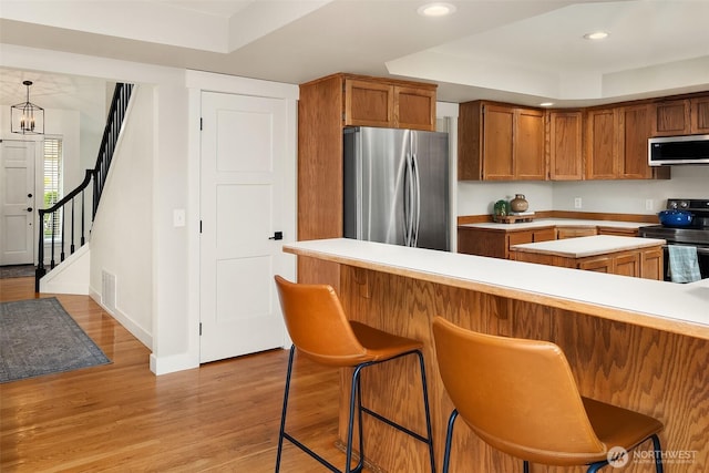 4624 SW 329th Way, Federal Way, WA 98023 - kitchen with appliances with stainless steel finishes, light countertops, a tray ceiling, brown cabinets, and a breakfast bar