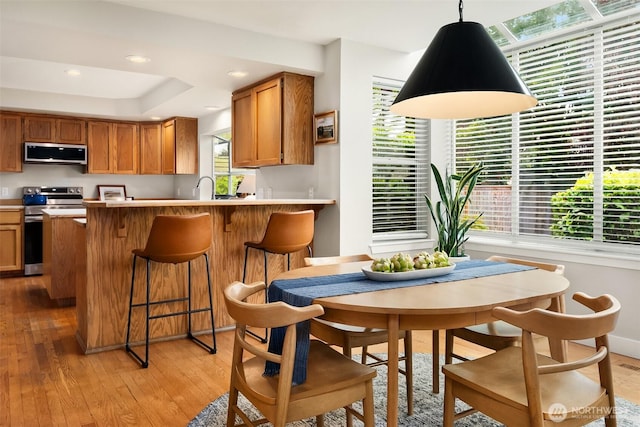4624 SW 329th Way, Federal Way, WA 98023 - kitchen with appliances with stainless steel finishes, light wood-style floors, brown cabinetry, light countertops, and a peninsula