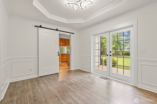27701 NE 145th Pl, Duvall, WA 98019 - empty room featuring a decorative wall, a barn door, wood finished floors, ornamental molding, and a wainscoted wall