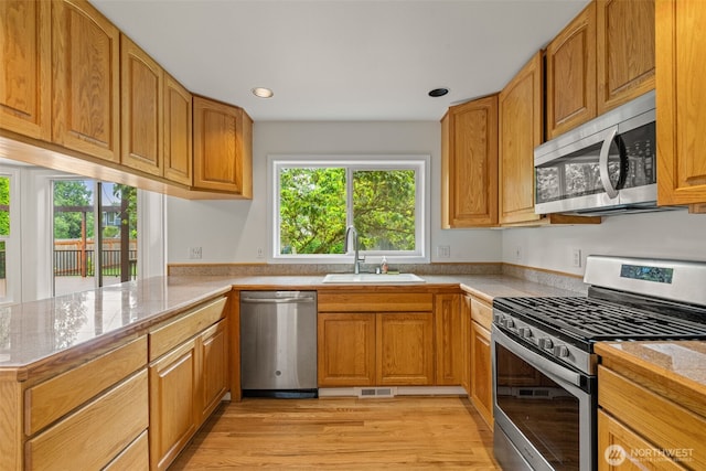 27701 NE 145th Pl, Duvall, WA 98019 - kitchen featuring appliances with stainless steel finishes, a peninsula, light wood finished floors, recessed lighting, and brown cabinetry