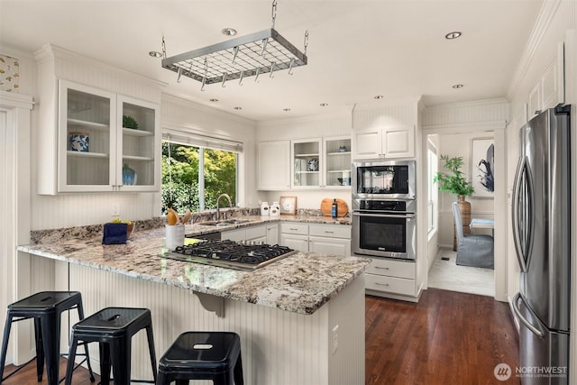 23976 SE 40th Pl, Sammamish, WA 98029 - kitchen with appliances with stainless steel finishes, a sink, a peninsula, dark wood finished floors, and ornamental molding
