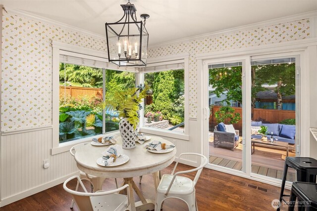 23976 SE 40th Pl, Sammamish, WA 98029 - dining space featuring dark wood finished floors, crown molding, a chandelier, a wainscoted wall, and wallpapered walls