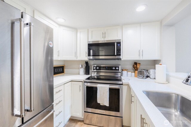 130 SW 116th St Unit F32, Seattle, WA 98146 - kitchen with stainless steel appliances, a sink, light countertops, white cabinets, and recessed lighting