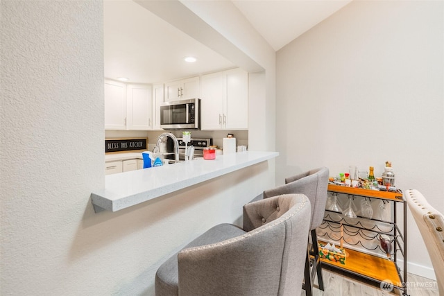 130 SW 116th St Unit F32, Seattle, WA 98146 - kitchen with stainless steel microwave, white cabinetry, light countertops, a sink, and recessed lighting