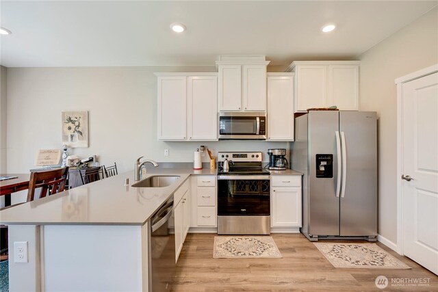 8713 E Gilman Ave, Arlington, WA 98223 - kitchen with appliances with stainless steel finishes, a sink, light wood finished floors, a peninsula, and white cabinetry