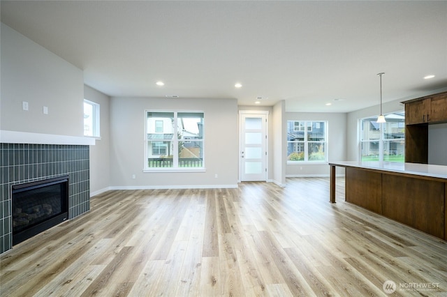 14516 204th Ave E Unit 895, Bonney Lake, WA 98391 - unfurnished living room with light wood-type flooring, a tiled fireplace, plenty of natural light, baseboards, and recessed lighting