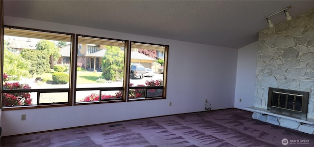 10622 44th Ave SE, Everett, WA 98208 - unfurnished living room with vaulted ceiling, a textured ceiling, carpet floors, a fireplace, and baseboards