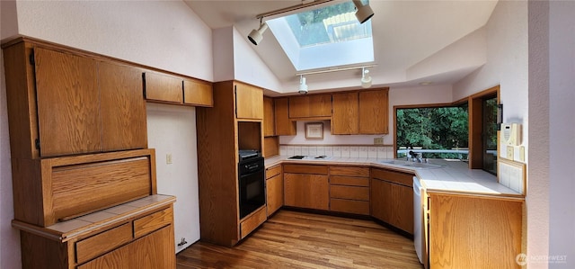 10622 44th Ave SE, Everett, WA 98208 - kitchen with tile counters, a skylight, a sink, light wood-style floors, and track lighting