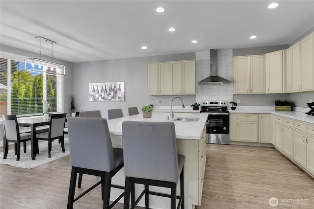 10617 Rosewood Ave Unit A, Everett, WA 98204 - kitchen featuring electric stove, wall chimney exhaust hood, a sink, a breakfast bar area, and light countertops