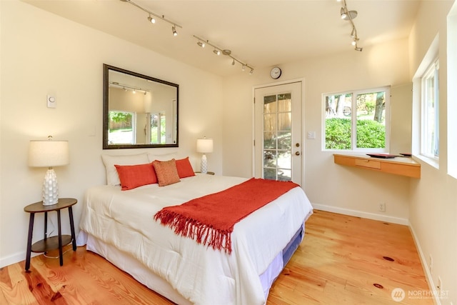11258 29th Ave SW, Seattle, WA 98146 - bedroom featuring rail lighting, access to exterior, wood finished floors, and baseboards