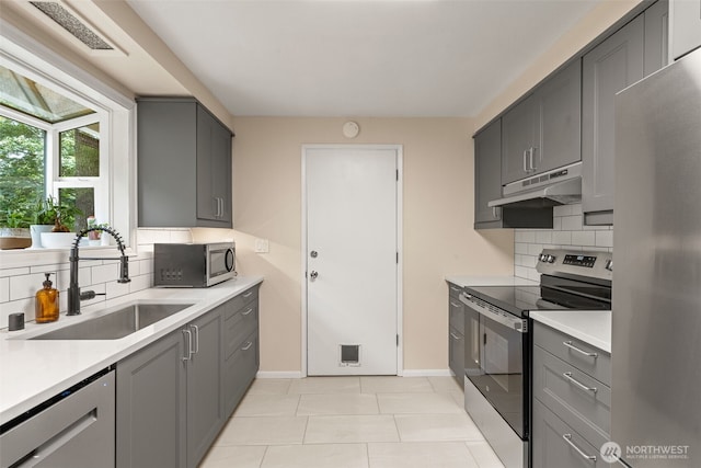 35804 15th Ave SW, Federal Way, WA 98023 - kitchen with stainless steel appliances, under cabinet range hood, gray cabinets, tasteful backsplash, and light countertops