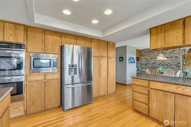 20219 SE 344th St, Auburn, WA 98092 - kitchen with appliances with stainless steel finishes, a raised ceiling, decorative backsplash, light wood finished floors, and recessed lighting