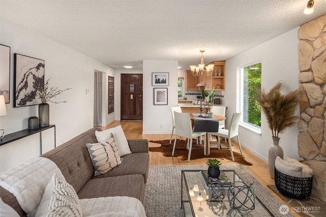 20101 61st Pl W Unit E-308, Lynnwood, WA 98036 - living room featuring a chandelier, light wood finished floors, a textured ceiling, and baseboards
