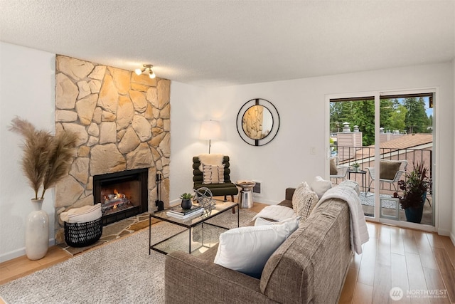 20101 61st Pl W Unit E-308, Lynnwood, WA 98036 - living room with wood finished floors, a stone fireplace, baseboards, and a textured ceiling