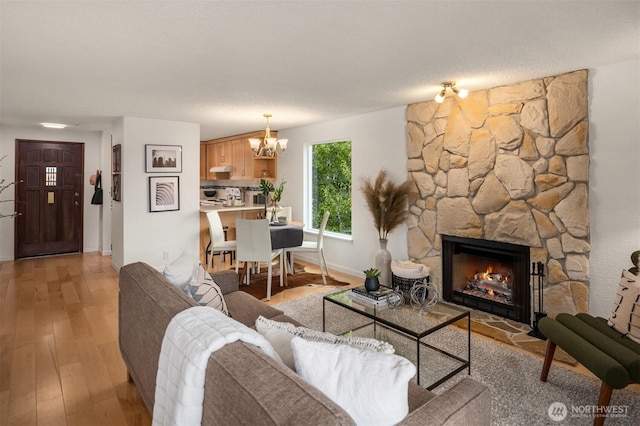 20101 61st Pl W Unit E-308, Lynnwood, WA 98036 - living room featuring a chandelier, a fireplace, baseboards, and light wood finished floors