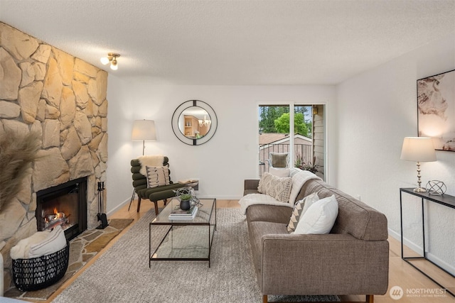 20101 61st Pl W Unit E-308, Lynnwood, WA 98036 - living area featuring a stone fireplace, a textured ceiling, baseboards, and wood finished floors