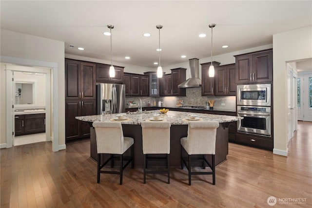 24332 NE 8th Pl, Sammamish, WA 98074 - kitchen with stainless steel appliances, wall chimney exhaust hood, dark brown cabinetry, decorative backsplash, and recessed lighting