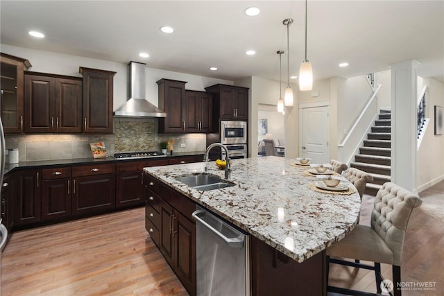 24332 NE 8th Pl, Sammamish, WA 98074 - kitchen with a sink, wall chimney range hood, appliances with stainless steel finishes, a breakfast bar, and light wood-type flooring