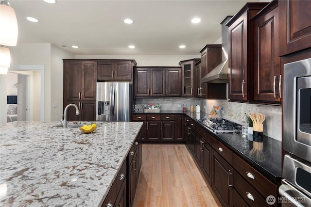 24332 NE 8th Pl, Sammamish, WA 98074 - kitchen featuring appliances with stainless steel finishes, a sink, light stone countertops, light wood-style floors, and decorative backsplash