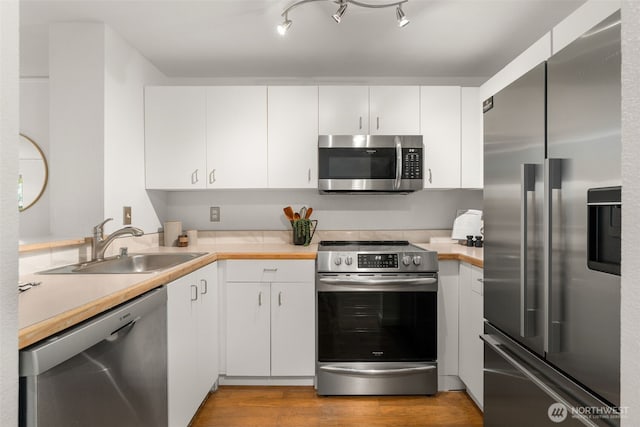 2244 13th Ave W Unit 106, Seattle, WA 98119 - kitchen with stainless steel appliances, light countertops, white cabinets, and light wood-style flooring