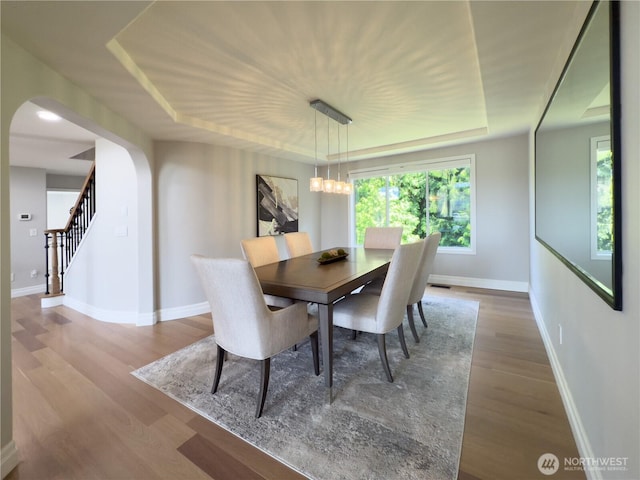 1621 Edgemoor Ln, Everett, WA 98203 - dining space featuring arched walkways, baseboards, wood finished floors, a tray ceiling, and stairway