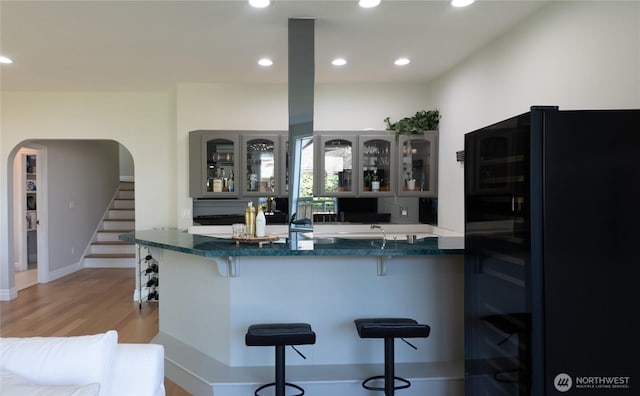 1621 Edgemoor Ln, Everett, WA 98203 - kitchen with refrigerator, arched walkways, a breakfast bar area, light wood-style flooring, and glass insert cabinets