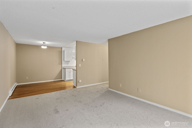 750 N 143rd St Unit 211, Seattle, WA 98133 - spare room with a baseboard radiator, light carpet, baseboards, and a textured ceiling