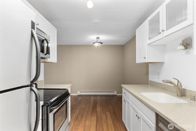 750 N 143rd St Unit 211, Seattle, WA 98133 - kitchen featuring appliances with stainless steel finishes, a baseboard radiator, white cabinetry, a sink, and dark wood finished floors