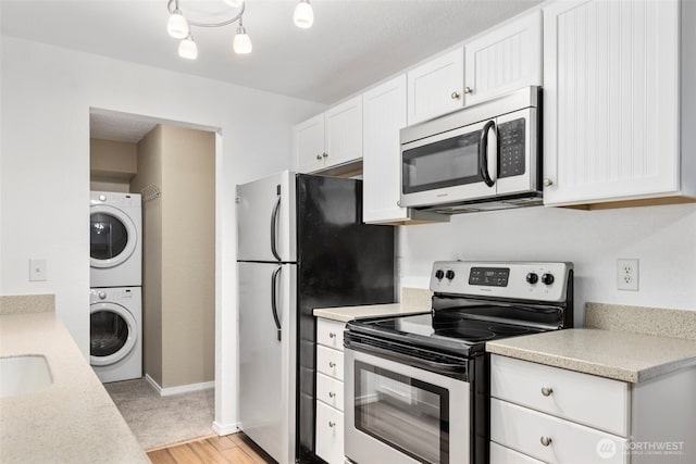 750 N 143rd St Unit 211, Seattle, WA 98133 - kitchen with stainless steel appliances, stacked washing machine and dryer, light countertops, light wood finished floors, and white cabinets