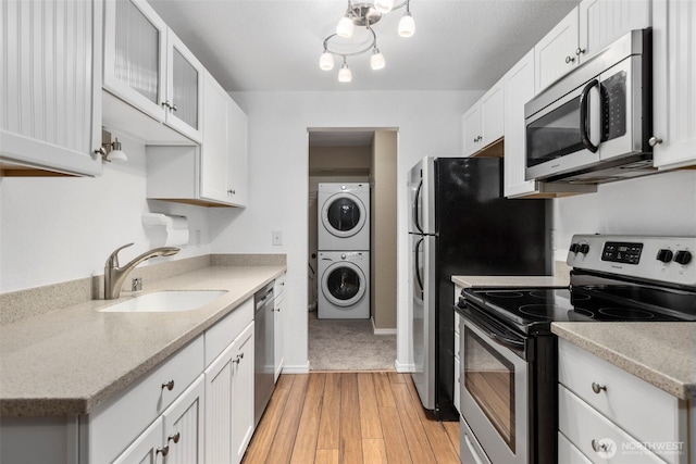 750 N 143rd St Unit 211, Seattle, WA 98133 - kitchen featuring stainless steel appliances, estacked washer and dryer, a sink, light countertops, and light wood finished floors