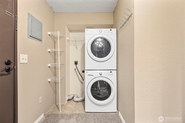 750 N 143rd St Unit 211, Seattle, WA 98133 - washroom featuring estacked washer and dryer, tile patterned floors, a textured ceiling, a textured wall, and electric panel