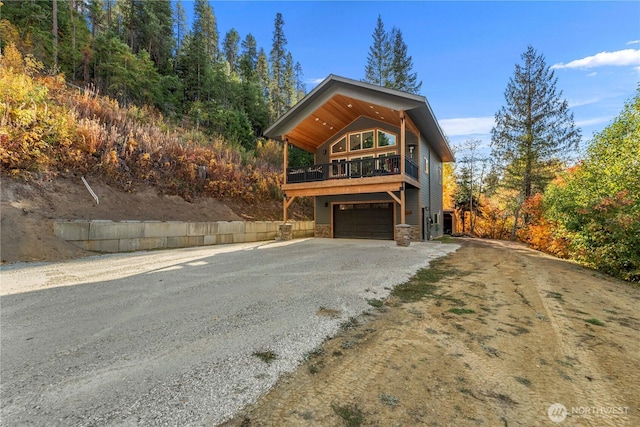 11175 Wending Ln, Leavenworth, WA 98826 - view of front of home featuring stone siding, driveway, a garage, and a balcony