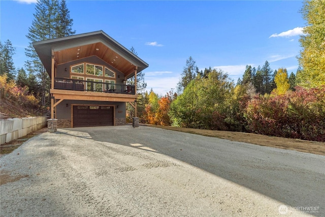 11175 Wending Ln, Leavenworth, WA 98826 - view of front of property featuring gravel driveway, a garage, stone siding, and a balcony