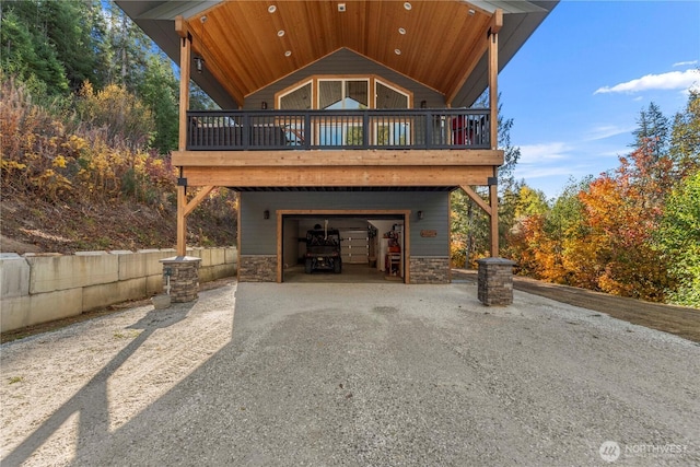 11175 Wending Ln, Leavenworth, WA 98826 - rear view of property featuring asphalt driveway, a garage, stone siding, and a wooden deck
