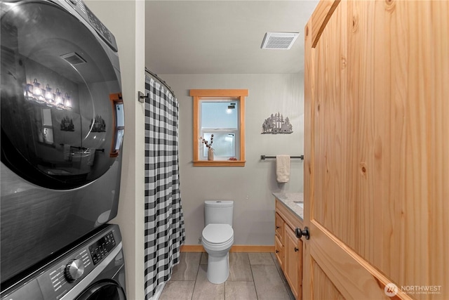 11175 Wending Ln, Leavenworth, WA 98826 - full bathroom featuring stacked washer and clothes dryer, toilet, vanity, tile patterned floors, and a shower with shower curtain