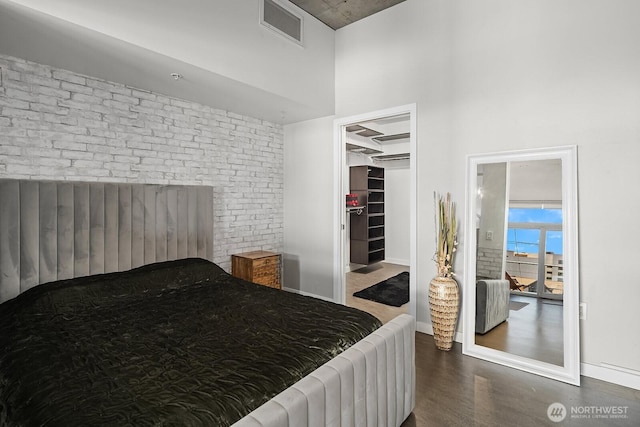 501 Roy St Unit T308, Seattle, WA 98109 - bedroom featuring wood finished floors, a walk in closet, radiator, baseboards, and brick wall