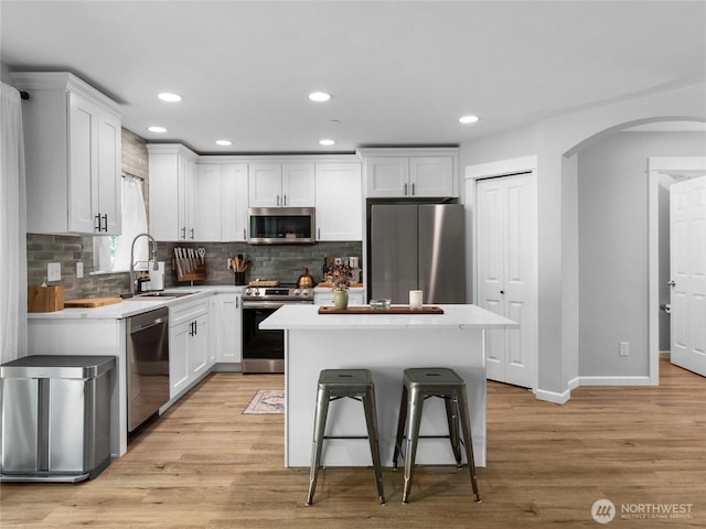 7600 Brianna Ct SE, Olympia, WA 98513 - kitchen with appliances with stainless steel finishes, a sink, arched walkways, white cabinetry, and tasteful backsplash