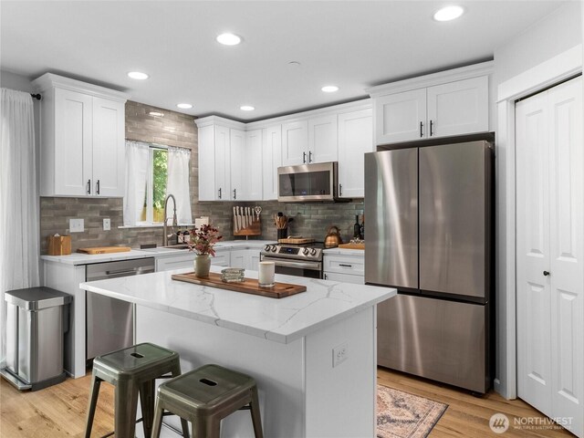 7600 Brianna Ct SE, Olympia, WA 98513 - kitchen featuring stainless steel appliances, white cabinetry, a sink, a center island, and backsplash