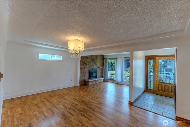 1035 Oakes Ave, Everett, WA 98201 - unfurnished living room with a textured ceiling, wood finished floors, a chandelier, baseboards, and a fireplace