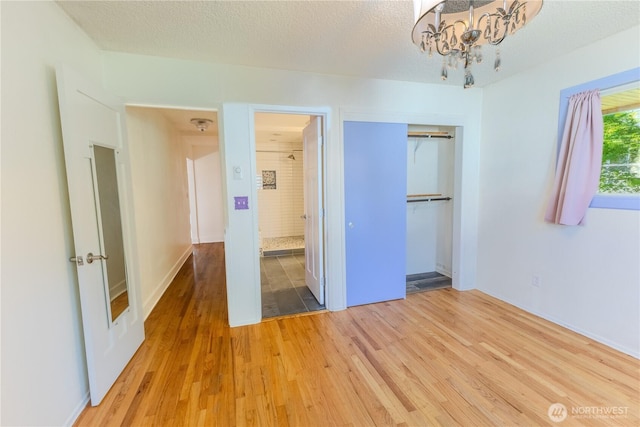 1035 Oakes Ave, Everett, WA 98201 - unfurnished bedroom with light wood finished floors, a chandelier, a closet, ensuite bath, and a textured ceiling