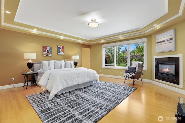 18737 63rd Ave NE, Kenmore, WA 98028 - bedroom featuring a raised ceiling, light wood-style floors, a glass covered fireplace, baseboards, and recessed lighting
