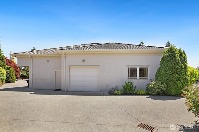 18737 63rd Ave NE, Kenmore, WA 98028 - view of side of property featuring driveway, a tile roof, a garage, and stucco siding