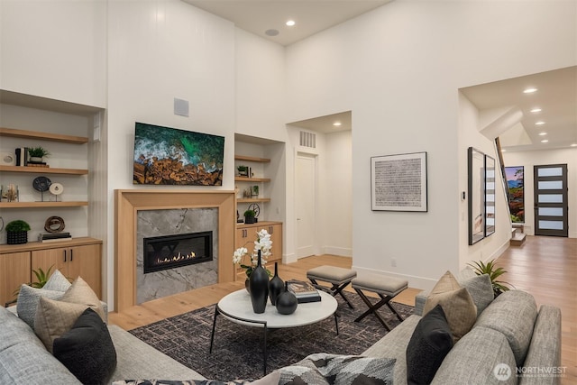 2505 166th Ave SE, Bellevue, WA 98008 - living area with light wood-type flooring, a premium fireplace, baseboards, a high ceiling, and built in features