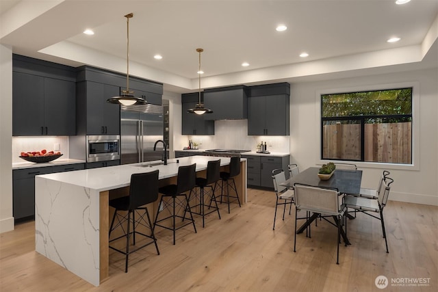 2505 166th Ave SE, Bellevue, WA 98008 - kitchen featuring a raised ceiling, built in appliances, a breakfast bar area, light wood-style flooring, and a spacious island
