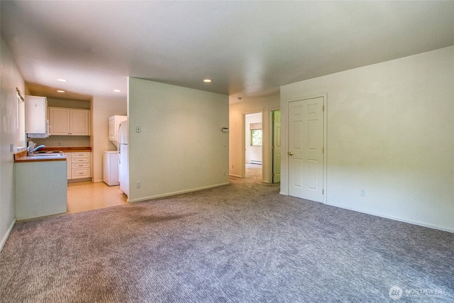 101 Tomihi Dr, Orcas Island, WA 98245 - unfurnished living room with a sink, light colored carpet, stacked washer and clothes dryer, recessed lighting, and baseboard heating
