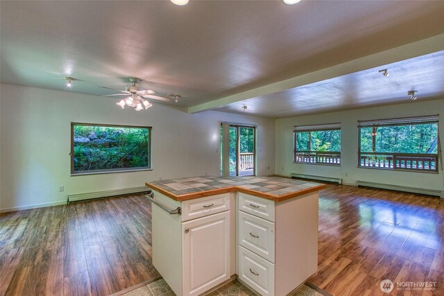 101 Tomihi Dr, Orcas Island, WA 98245 - kitchen featuring tile counters, open floor plan, baseboard heating, wood finished floors, and white cabinets