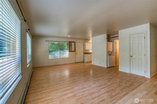 101 Tomihi Dr, Orcas Island, WA 98245 - unfurnished living room with estacked washer and dryer, light wood finished floors, baseboards, and a baseboard radiator