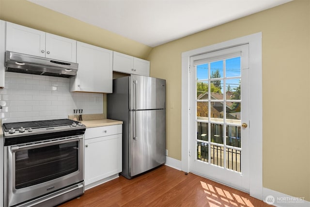 2321 Elm St, Bellingham, WA 98225 - kitchen featuring appliances with stainless steel finishes, under cabinet range hood, decorative backsplash, white cabinetry, and wood finished floors