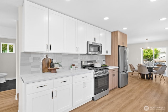 5041 Bowen Pl S, Seattle, WA 98118 - kitchen featuring stainless steel appliances, light wood finished floors, white cabinets, recessed lighting, and backsplash