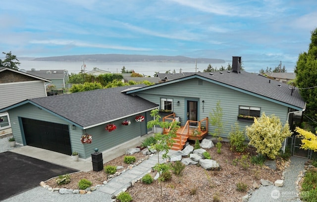 1083 N Vista Del Monte St, Camano Island, WA 98282 - view of front of house with roof with shingles, an attached garage, a deck with water view, asphalt driveway, and a chimney